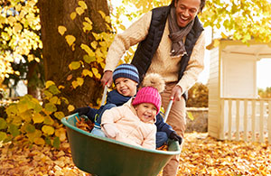 Father pushing kids in wheel barrel 