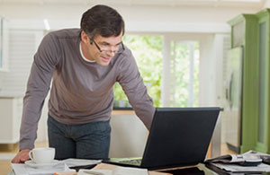 Man standing looking at laptop